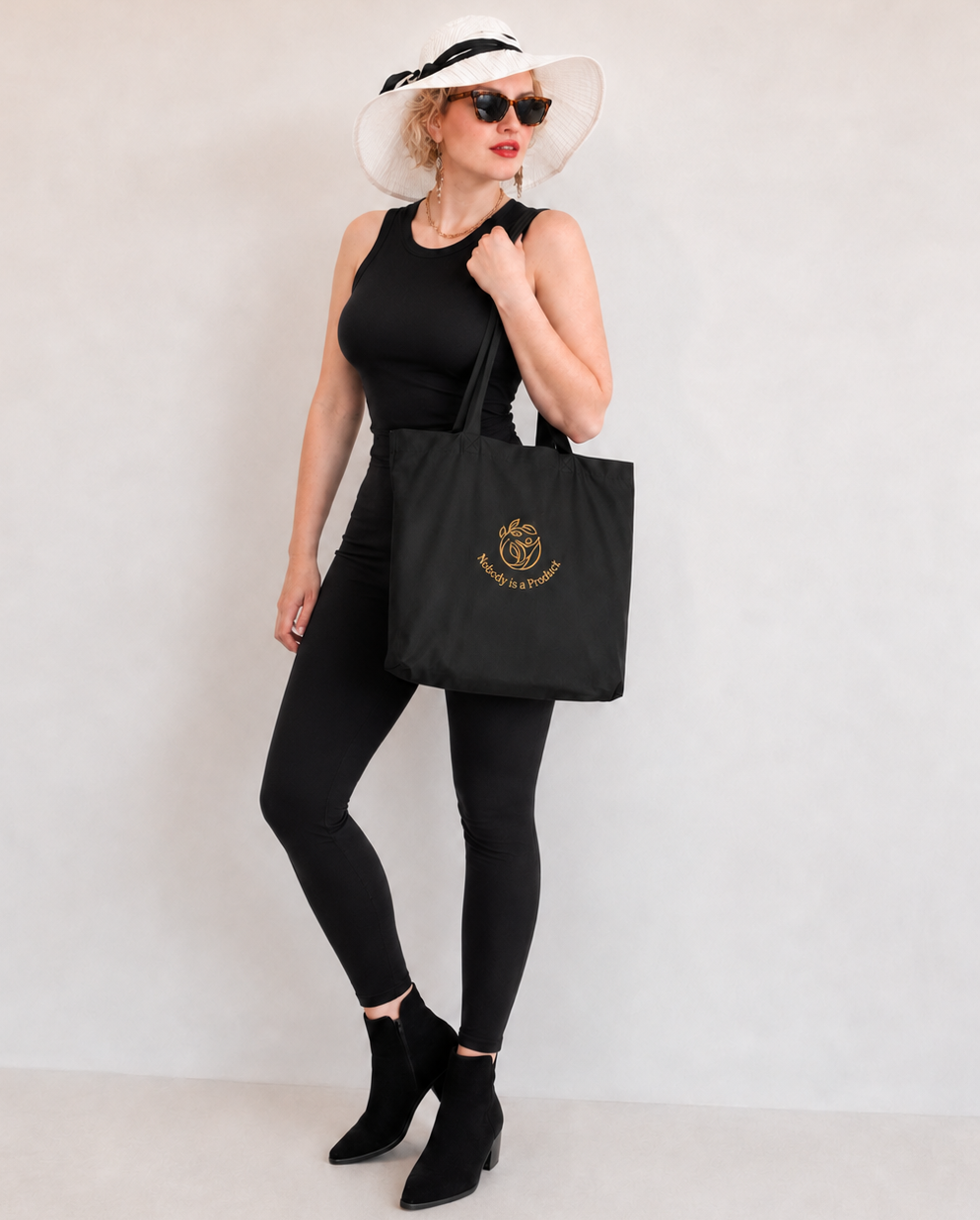 NoBody is a Product.  Organic cotton regular size black Tote bag (embroidered gold logo)
